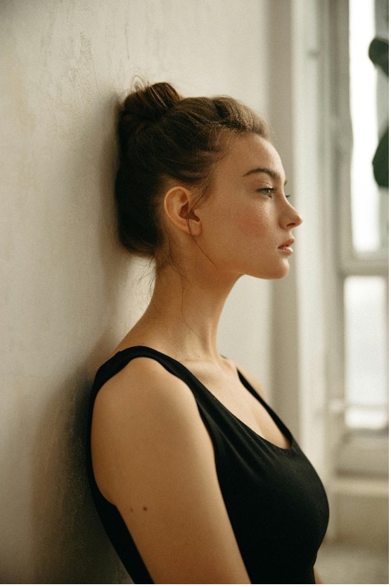 woman stretching neck against a wall.